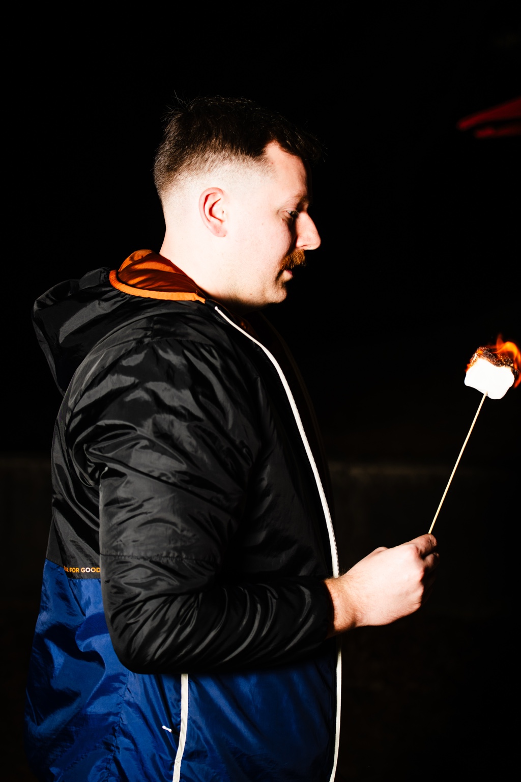 A visitor toasting a marshmallow outdoors at night