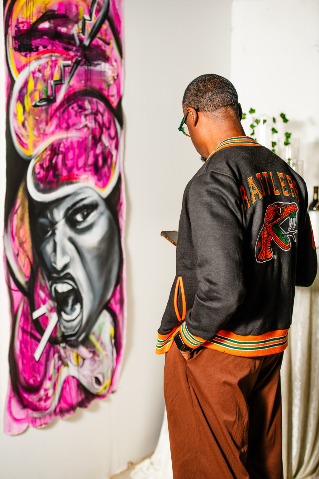 A visitor standing beside a vivid pink and black portrait painting