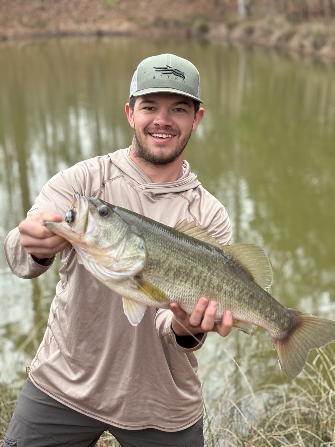 A visitor holding a freshly caught fish beside the lake