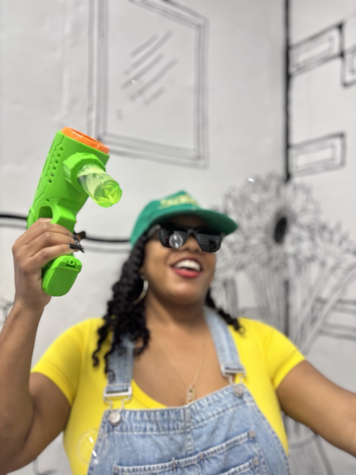 A smiling visitor in overalls holding a colorful bubble toy in an art space